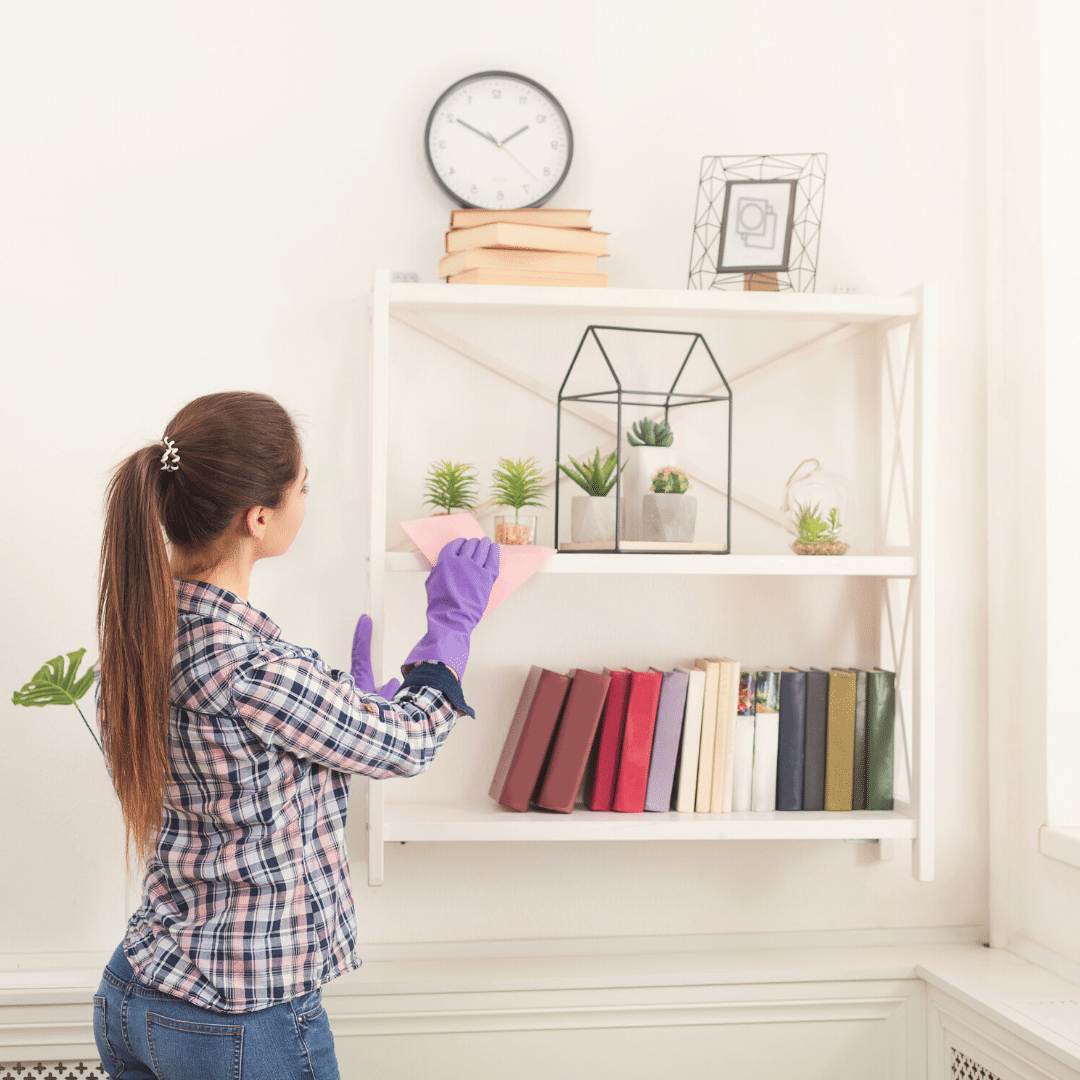 Woman cleaning bookshelves to stay productive during a lockdown.